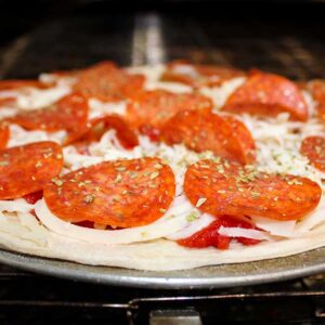 Ledgens Italian style Pizza topped with fresh pepperoni, homemade red sauce and dough slides into the oven at Texas' best pizzeria restaurant